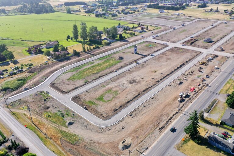 Aerial view of a planned residential development with graded lots and new roads in Western Washington
