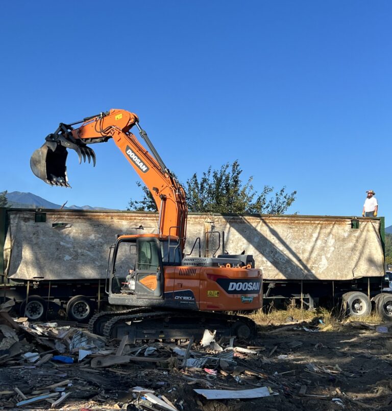 Excavator demolishing an old mobile home to prepare the property for a replacement home