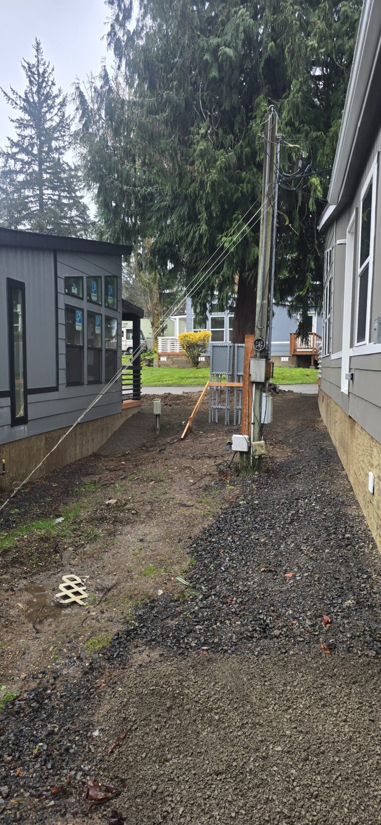 Graded gravel drainage path along the side of a newly installed manufactured home