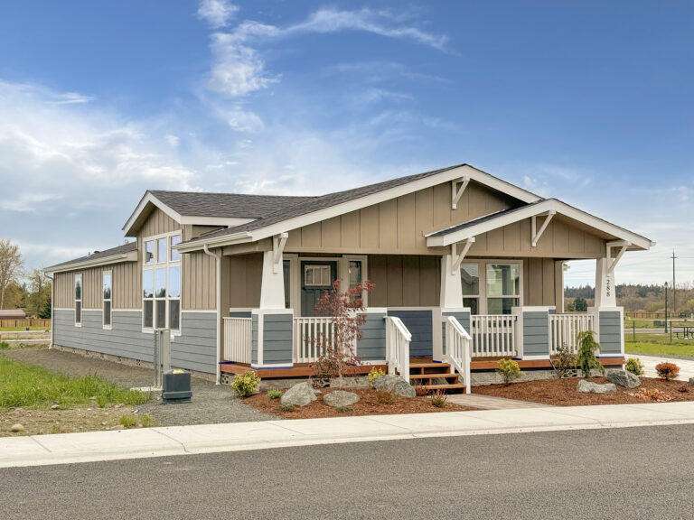 Craftsman-style manufactured home with a covered front porch, landscaping and paver walkway