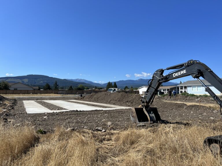 Excavator preparing a site with concrete footings for a manufactured home foundation